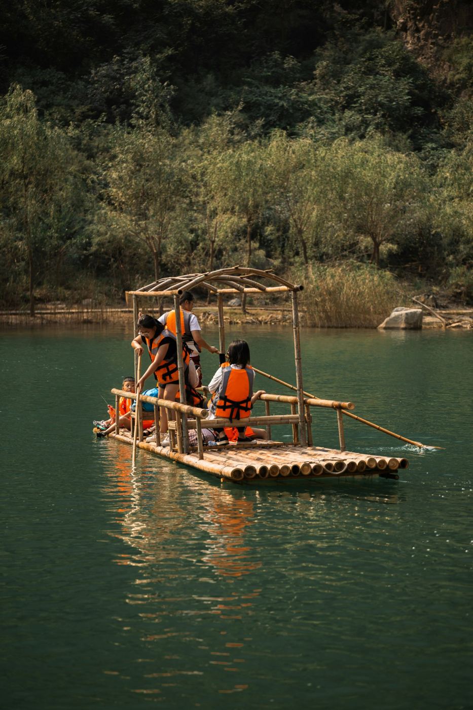 A bamboo raft drifting down a calm green river