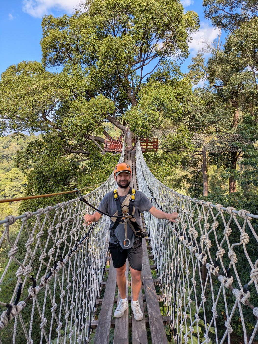 Liam in a helmet and harness on a rope bridge high in the jungle canopy outside Chiang Mai