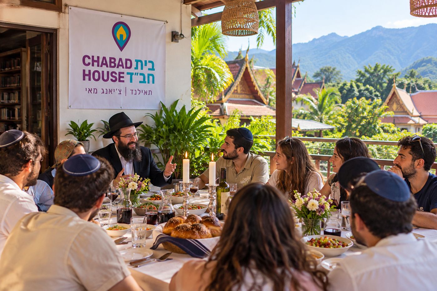 A Shabbos table with candles, challah and wine on a terrace in Chiang Mai