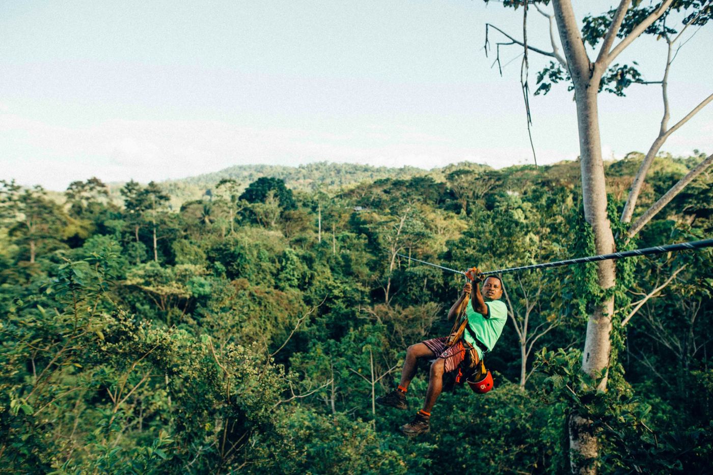 A zipliner flying over a green jungle canopy