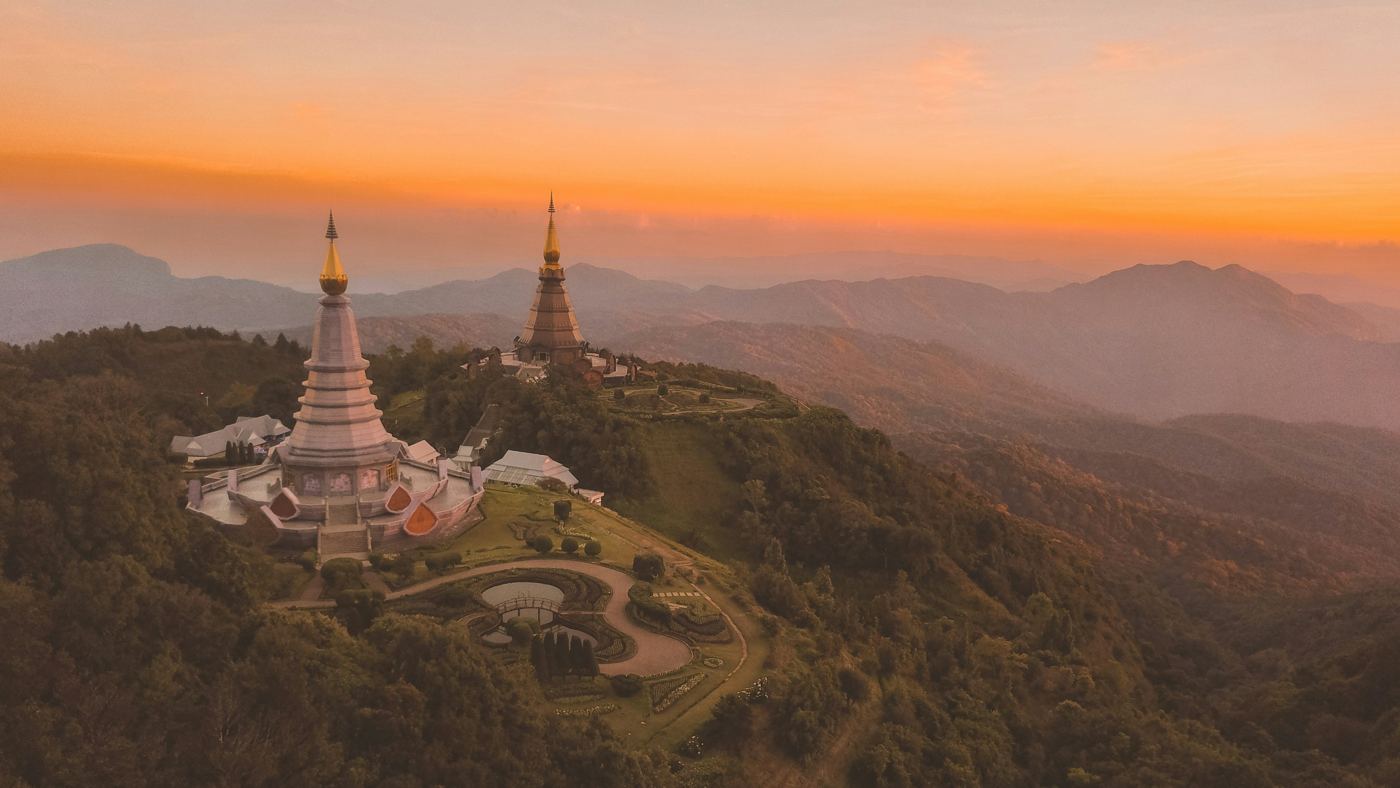 The twin royal pagodas of Doi Inthanon at sunset above layers of mountains