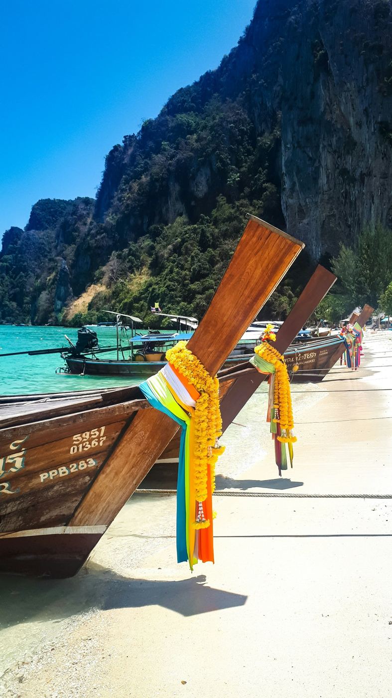 Longtail boats decorated with garlands on a white-sand beach in Phi Phi