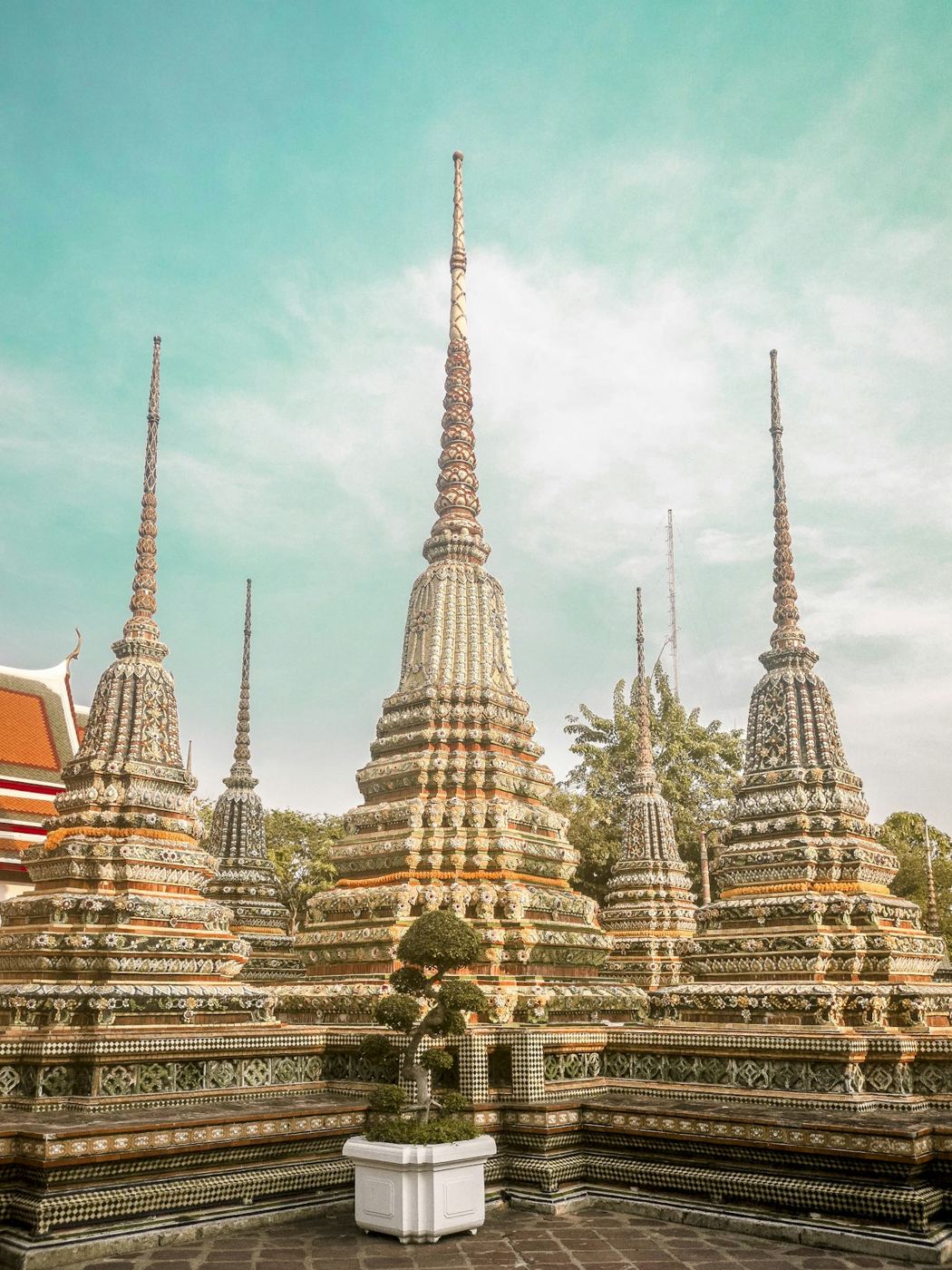 Tall mosaic-tiled spires against a teal sky at Wat Pho