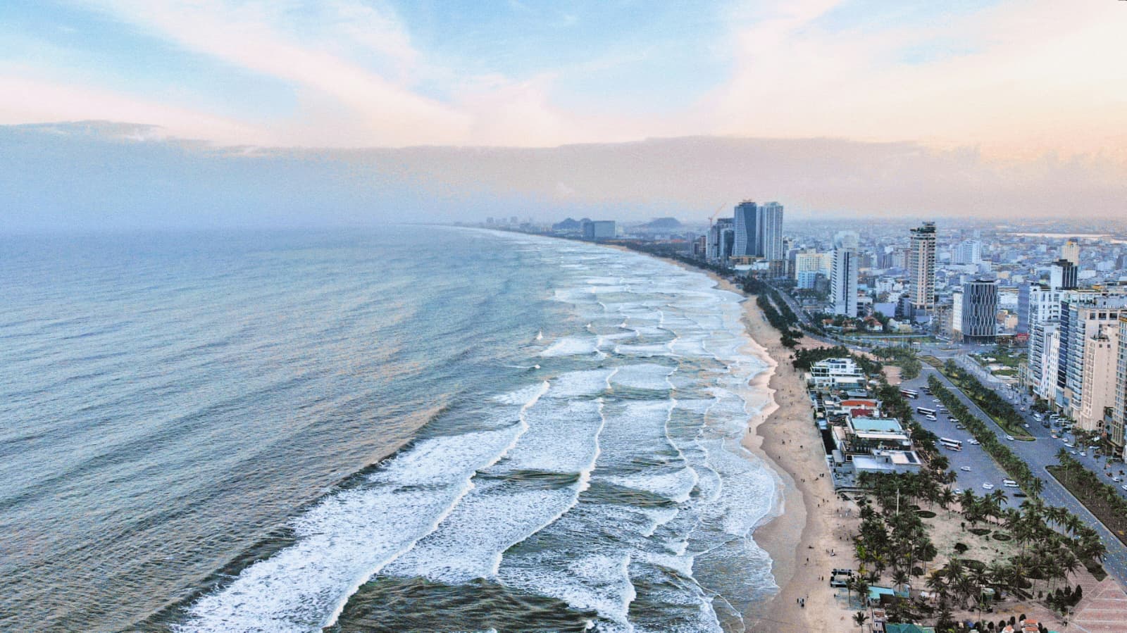 Aerial view of Da Nang's beach, rolling waves and seafront hotel towers