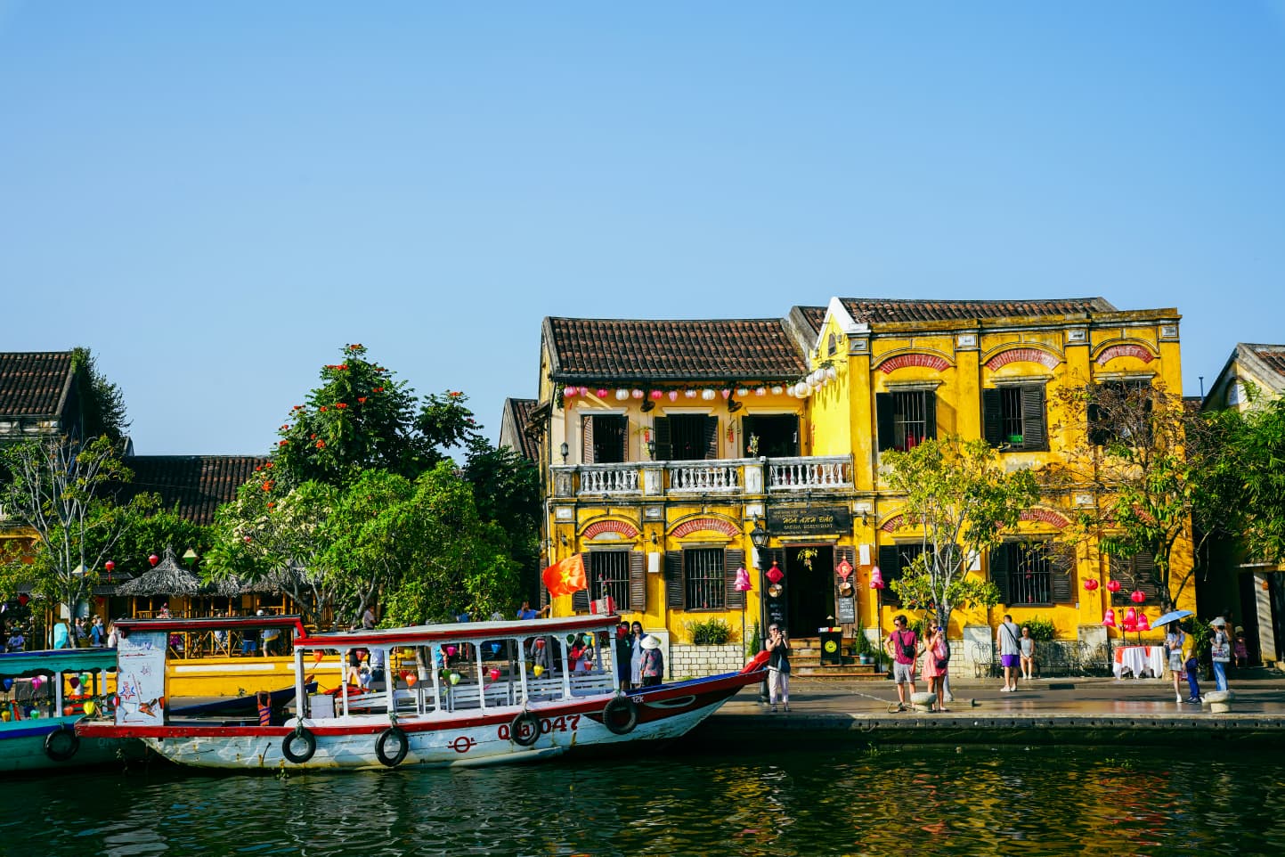Yellow colonial house and a wooden boat on the river in Hoi An's Ancient Town